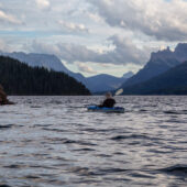 Adventurous Man Kayaking in Glacier Lake surrounded by the Canadian Rocky Mountains in Background